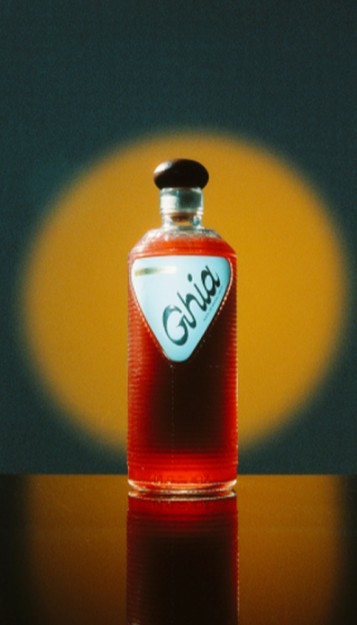 Ghia apéritif bottle spotlit against a glowing yellow backdrop