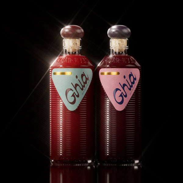 Two non-alcoholic beverages in Berry Apéritif & Original bottles with ribbed glass, cork tops, and bold branding; one with a light blue label on the left, the other with a pink label on the right.