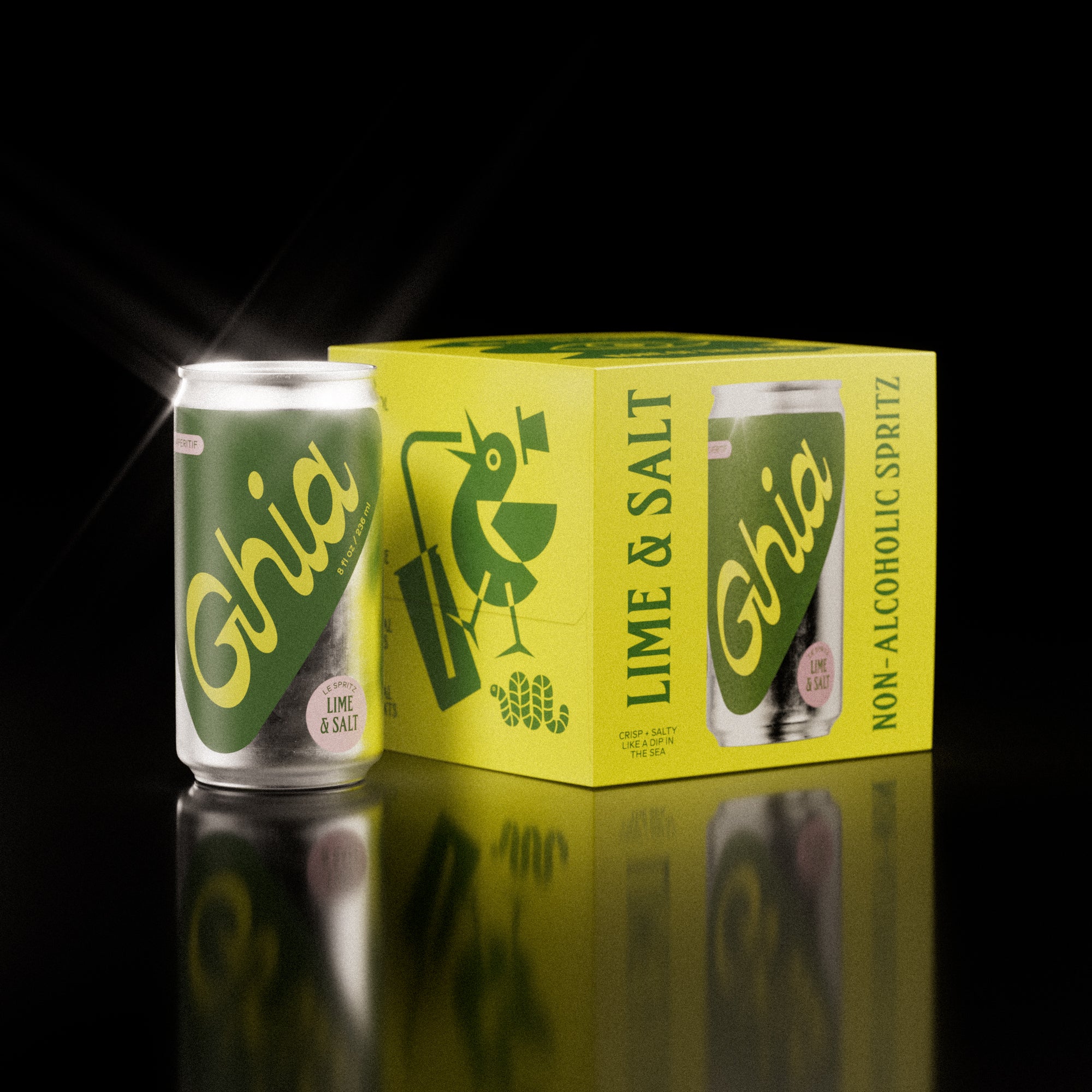 A pack of four Ghia Lime & Salt non-alcoholic spritz cans with a bright yellow box featuring playful illustrations. One can is placed beside the box, reflecting on a surface.