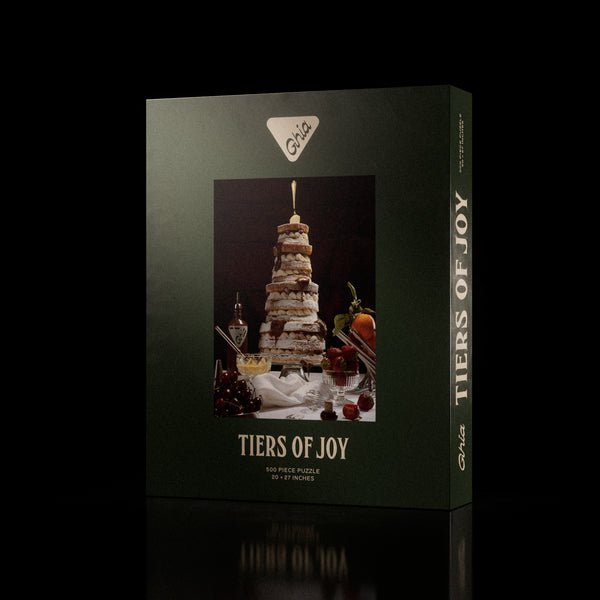Ghia-branded 500-piece puzzle box featuring a whimsical illustration of a tall, layered dessert with candles and fruit.