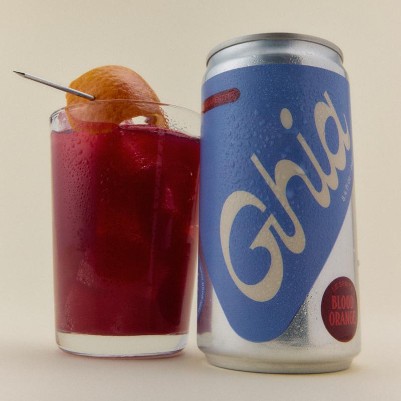 Ghia Le Spritz Blood Orange can beside a glass of red spritz garnished with an orange twist